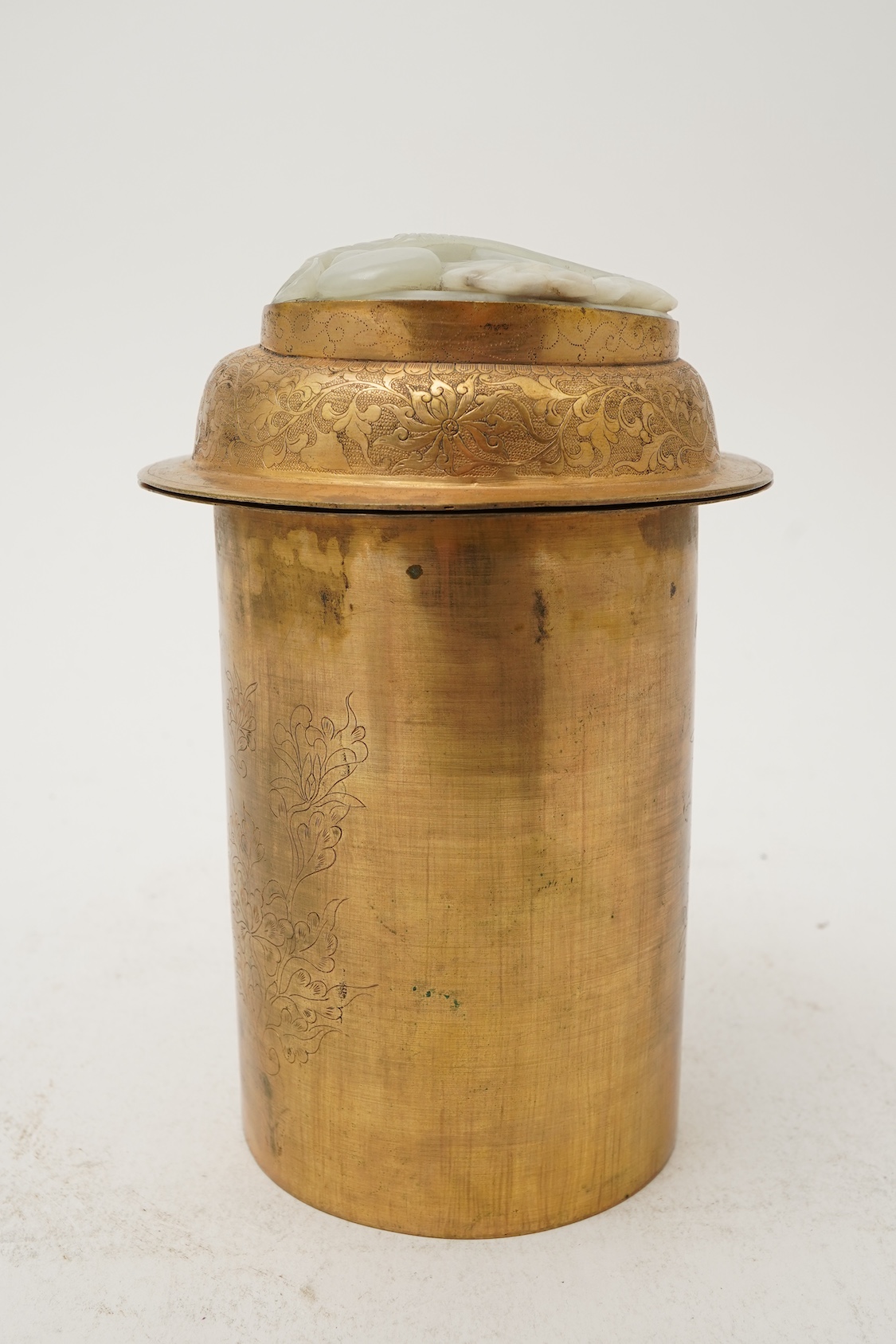 A Chinese pale celadon jade oval plaque, 17th/18th century, mounted on a late Qing gilt copper jar